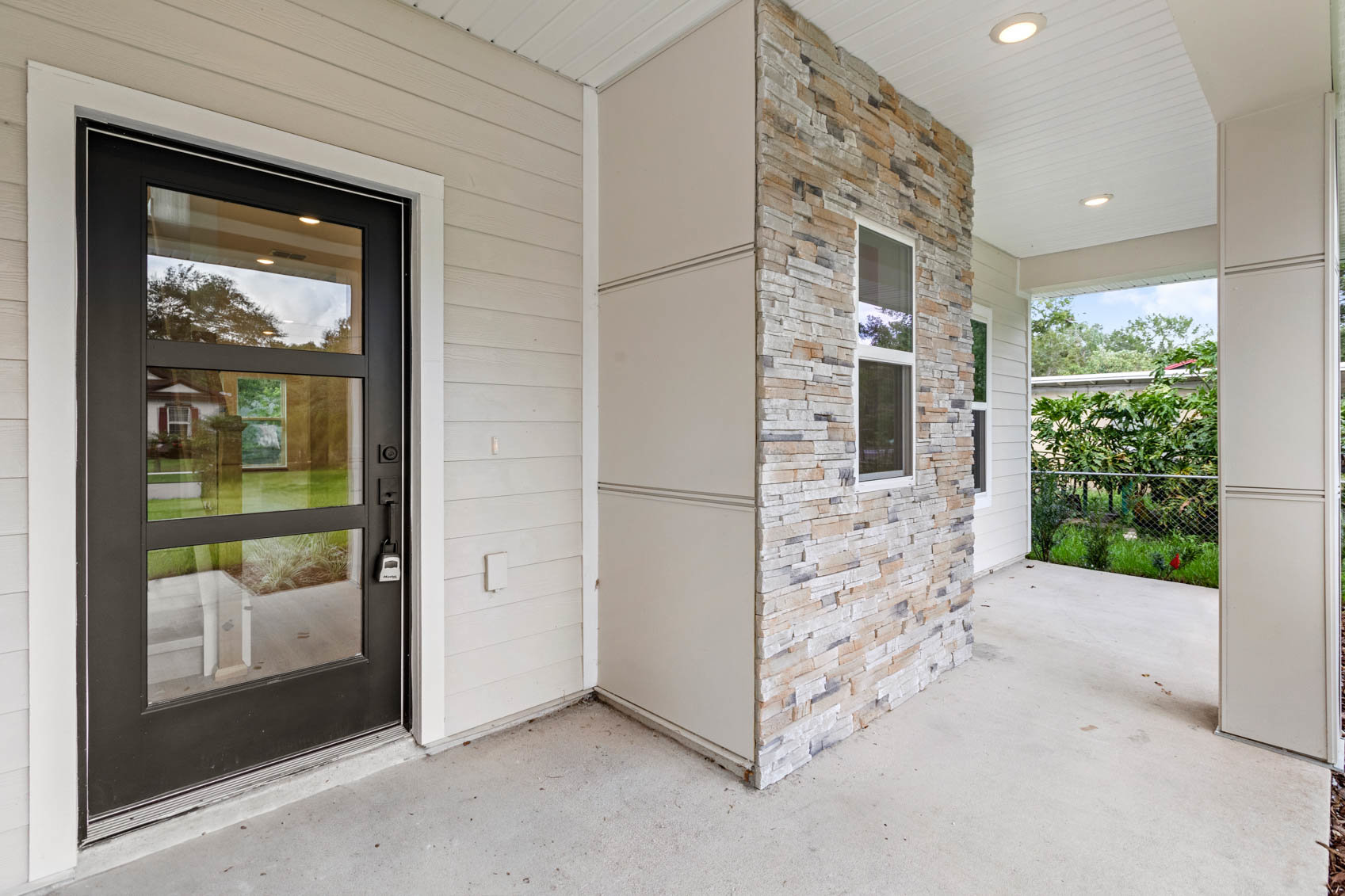 front porch with black door and brick wall